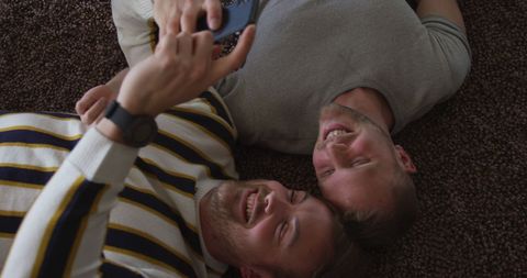 Joyful couple lying on carpet capturing moments together