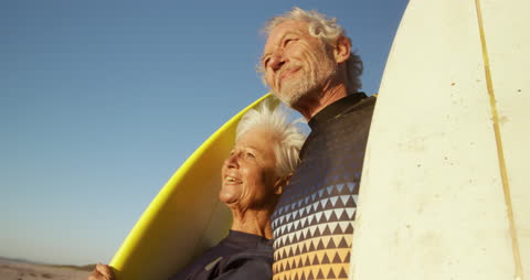Senior Couple Embracing with Surfboards at Beach