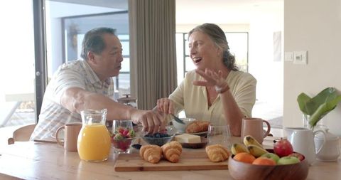 Senior Couple Enjoying Breakfast with Croissants and Fresh Fruit