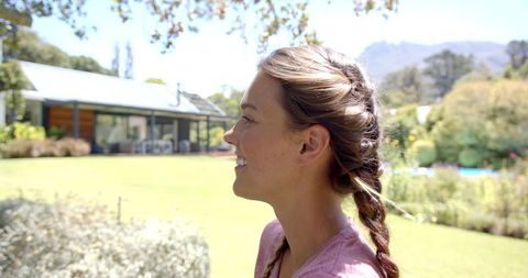 Smiling Woman with Braids Enjoying Sunny Backyard Garden