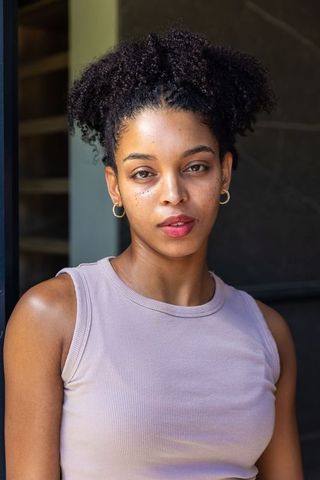 African american woman standing in doorway wearing gold hoop earrings and ribbed tank top