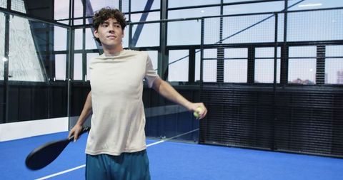 Male Padel Player Stretching with Racket on Blue Court
