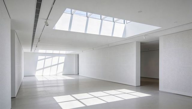 Minimalist white museum gallery featuring skylight grid shadows and modern architecture