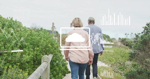 Senior couple walking coastal boardwalk with cloud tech overlay and nature trail