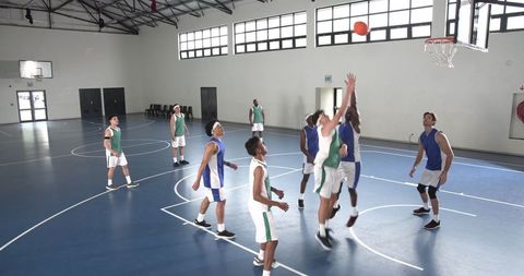 Basketball Players Competing in Indoor Gymnasium Game