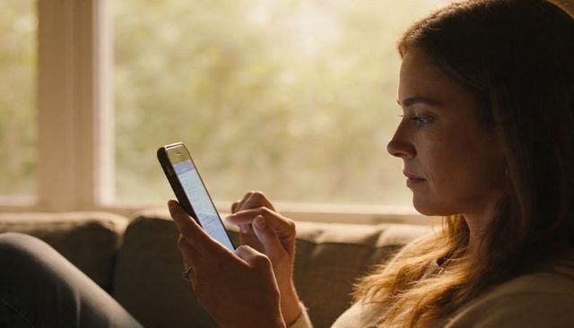 Woman using smartphone on couch at home during golden hour soft natural light relaxed pose