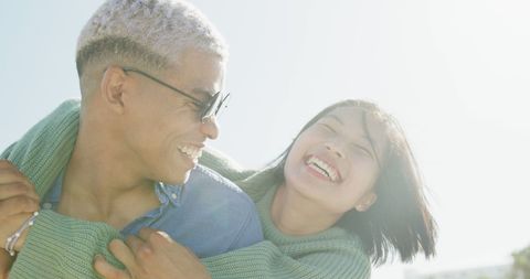 Joyful Couple Laughing Together Near Sea on Sunny Day