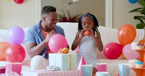 Father and Daughter Blowing Balloons for Birthday Celebration