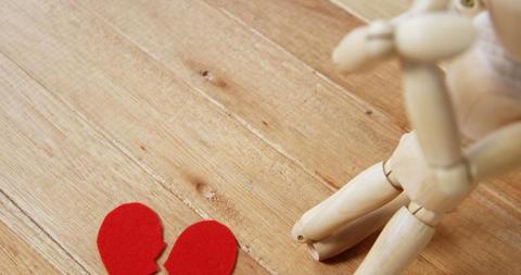 A wooden figure sits beside a broken heart cutout on a wooden surface, with copy space - Download Free Stock Photos Pikwizard.com