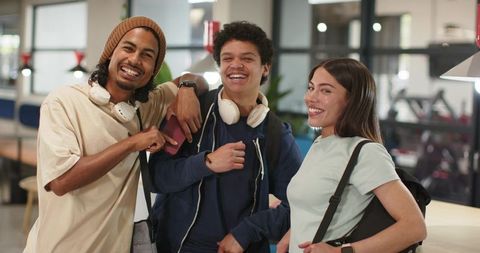 African american students smiling and posing in campus lounge with headphones backpacks