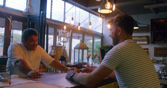 Customer having casual conversation with bartender in cozy cafe. Perfect for illustrating casual interactions, socializing in relaxed environments, or showcasing customer service moments. Great for adding a human element to hospitality industry content.