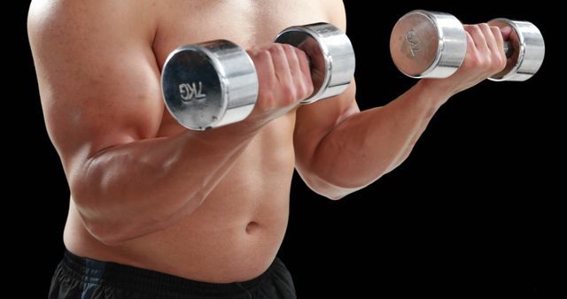 A young Caucasian man is working out with dumbbells, focusing on his bicep muscles, with copy space. His commitment to fitness is evident in his muscular physique and the intensity of his exercise routine.