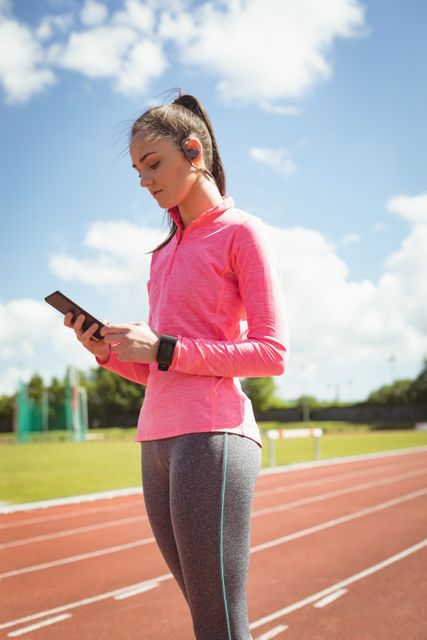 Young woman using mobile phone on a race track