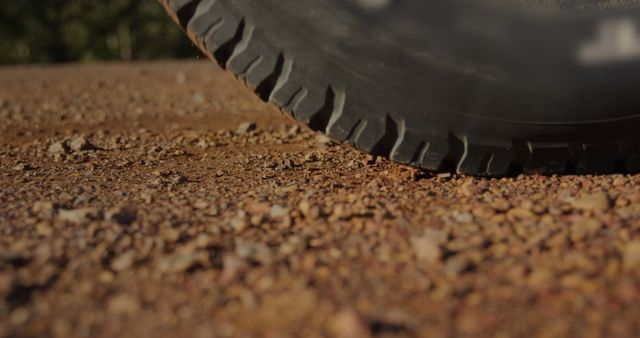 Close up of back wheels of a car driving off on grit during a road trip in the sunshine, they are on a road trip
