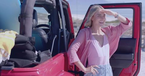Woman Enjoying Beach Adventure Beside Red Jeep with Surfboard