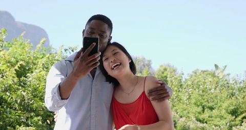 Interracial Couple Enjoying Moment with Smartphone Outdoors