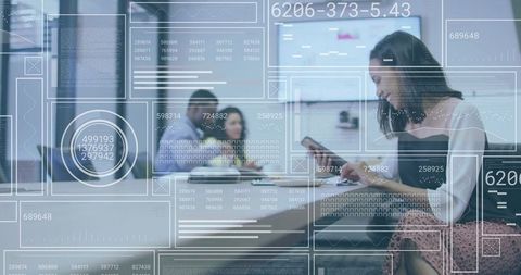 Woman tapping tablet with futuristic data overlays in coworking lounge, collaborative tech