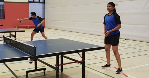 Teammates Competing in Table Tennis at Indoor Sports Hall