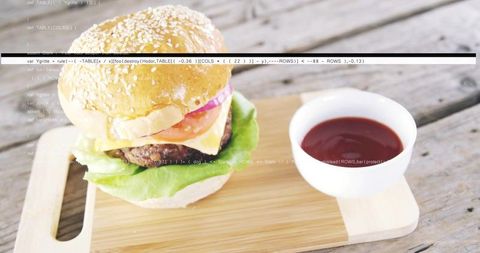 Sesame cheeseburger on rustic wooden cutting board with ketchup bowl and code overlay