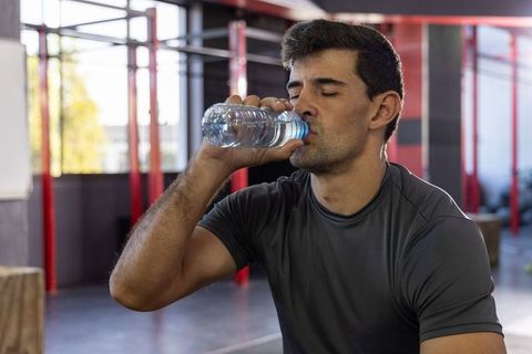 Man drinking water during functional fitness workout near red rig frames