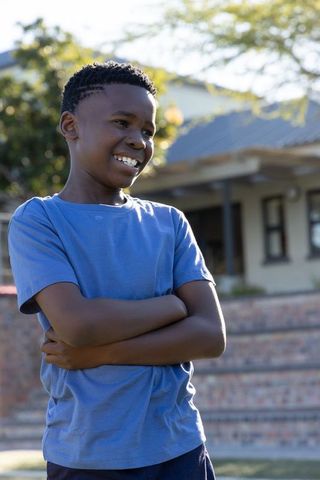 Smiling african american boy standing confidently in sunny suburban yard