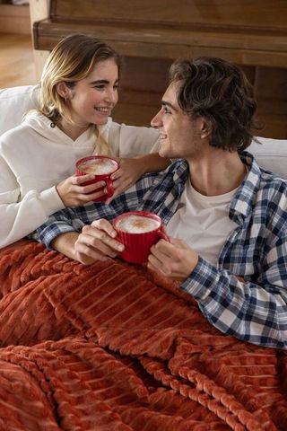 Couple Relaxing Under Blanket with Coffee at Home