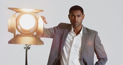 Confident Man Posing Beside Studio Spotlight in Business Attire