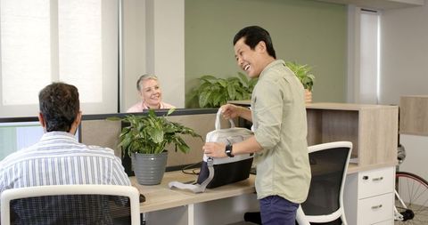 Diverse coworkers in open office discussing with laughter