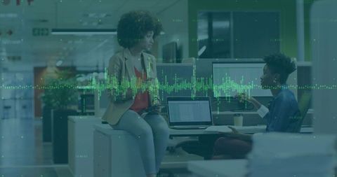 Female Colleagues Collaborating Over Laptops in Modern Office, Data Visualization Overlay