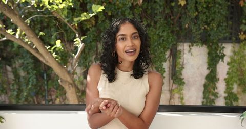 Elegant Woman Gesturing in Tranquil Outdoor Courtyard