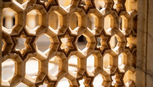 Sunlit carved jali screen casting geometric octagonal and six-pointed star shadows