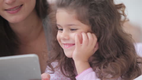 Mother and Daughter Smiling While Using Digital Tablet Together
