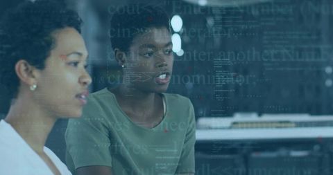Women collaborating and reviewing code on glass partition in modern tech workspace