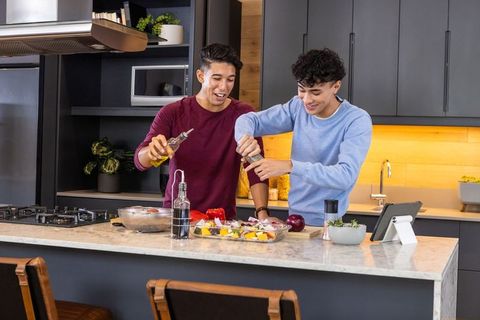 Young men cooking with vegetables in contemporary kitchen