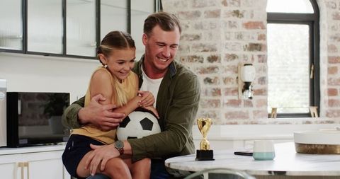 Father and Daughter Celebrating Soccer Achievement at Home