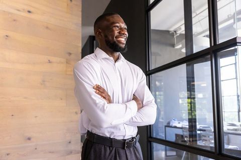 Confident Businessman Crossing Arms in Modern Office Space