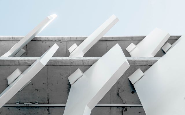 This image features a close-up of a modern architectural design, focusing on geometric shapes formed by concrete structures and steel beams. It highlights the minimalistic yet intricate details of contemporary architecture and can be used for architectural portfolios, minimalist design blogs, urban development presentations, or industrial style advertisements.