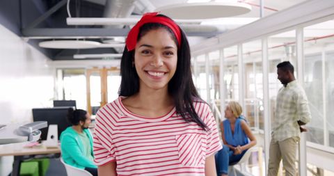 Confident young professional smiling at camera presents positive and welcoming work environment. Her cheerful personality and business casual attire are ideal for showcasing modern and inclusive office culture or material highlighting women empowerment and multicultural teams in corporate branding or HR presentations.