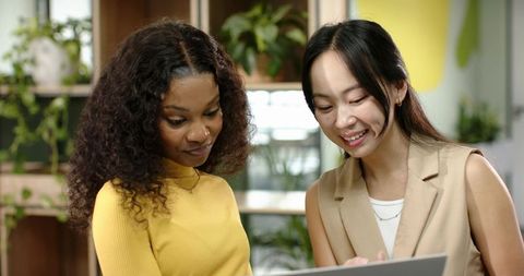 Diverse Businesswomen Collaborating Over Laptop in Modern Office