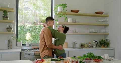 Happy Couple Embracing in Modern Kitchen with Fresh Vegetables