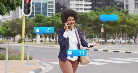 Smiling businesswoman walking at crosswalk using smartphone with social media notifications