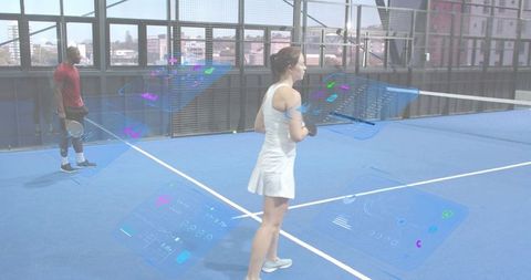Female tennis player training with augmented reality coaching panels on indoor blue court