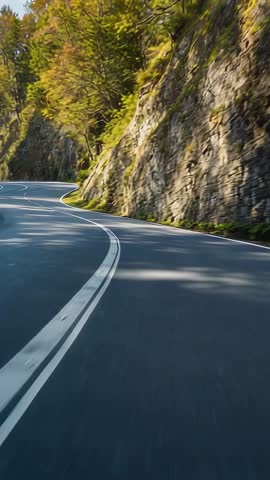 Vertical Driving Shot Tracing Winding Mountain Road Beside Rugged Rock Cliff
