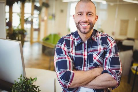 Smiling Businessman with Arms Crossed in Modern Office