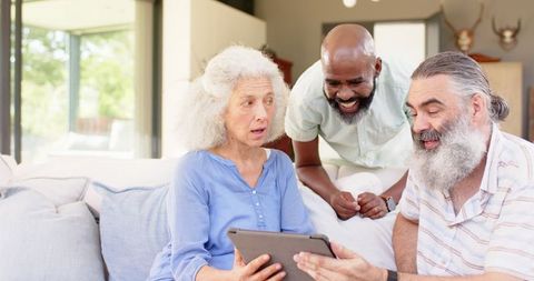 Senior Friends Having Fun with Tablet on Cozy Living Room Sofa
