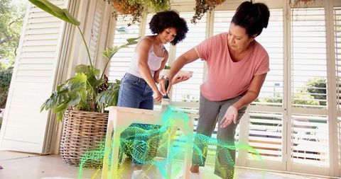 Women painting table on sunny porch with augmented reality overlay for diy home projects