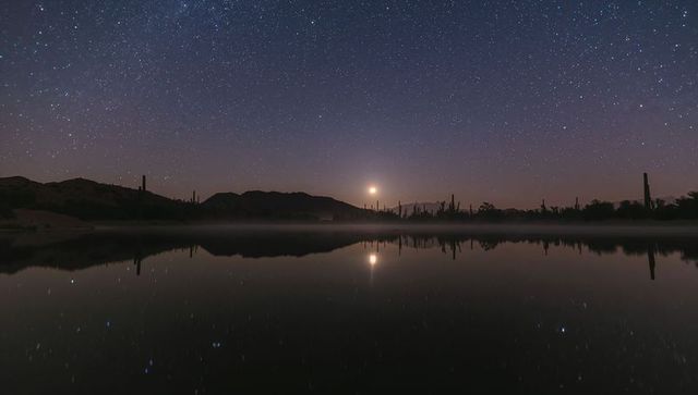Moonrise Reflecting on Calm Desert Lake with Saguaro Silhouettes under Starry Night Sky