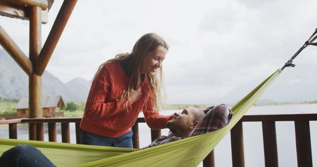 Woman Smiling with Man Resting in Hammock on Lakeside Deck - Download Free Stock Images Pikwizard.com
