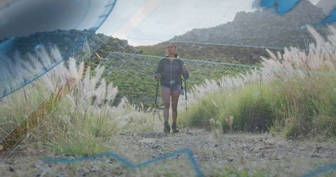 Confident Woman Exploring Scenic Valley Trail with Trekking Poles
