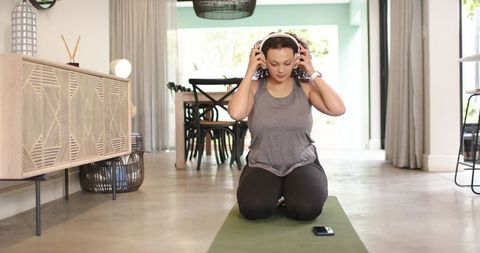 African american woman preparing for home yoga routine with headphones and smartphone